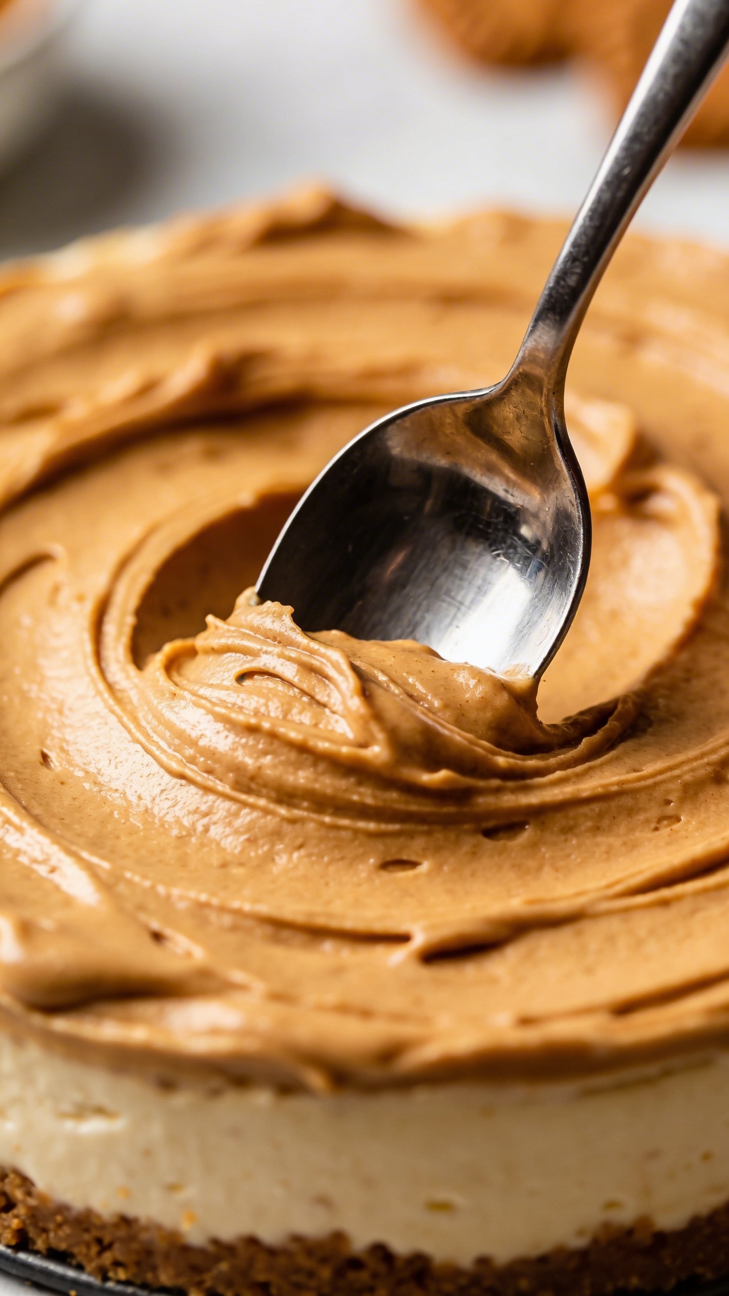 **Single spoon dipping into creamy Biscoff cheesecake filling**